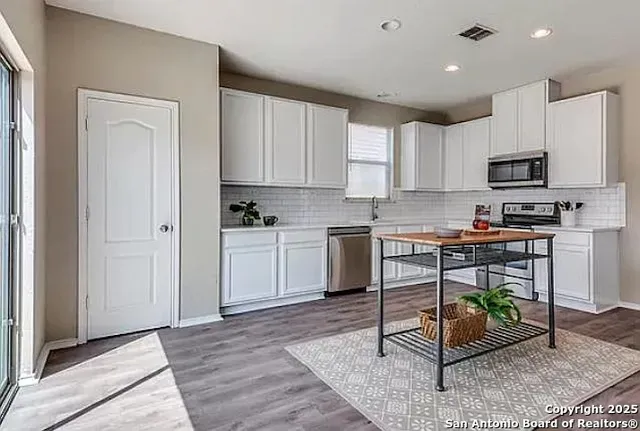 a kitchen with cabinets stainless steel appliances and a window