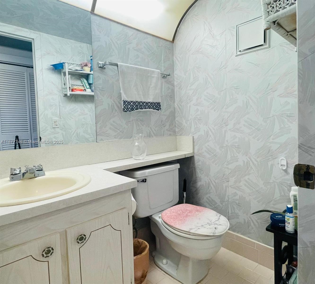 251 Suffolk F, Unit 251 Boca Raton, FL 33434 - Photo 5 of 25 a bathroom with a sink a toilet and a mirror
