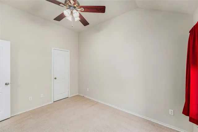 a view of an empty room and chandelier fan