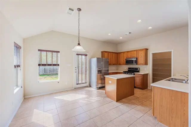 a kitchen with stainless steel appliances granite countertop a refrigerator a stove and a sink