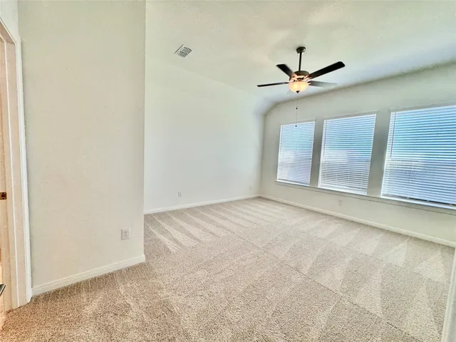 an empty room with a ceiling fan and carpet