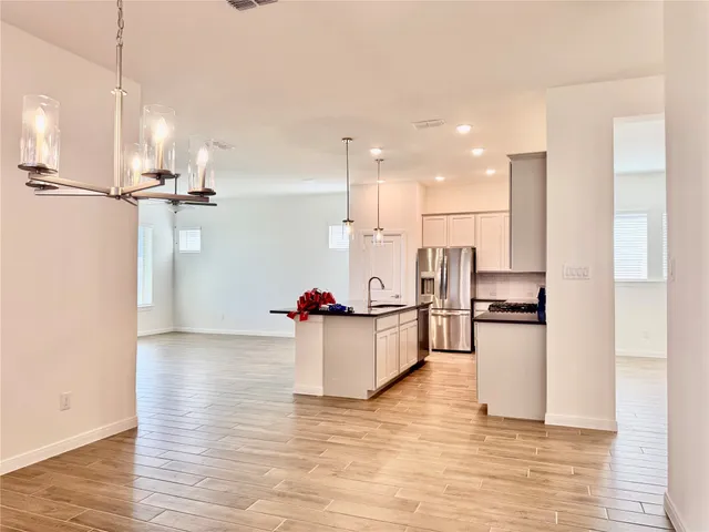 a kitchen with stainless steel appliances wooden floor and a refrigerator