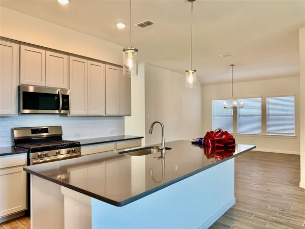 a kitchen with stainless steel appliances a sink a microwave a stove and a wooden floor