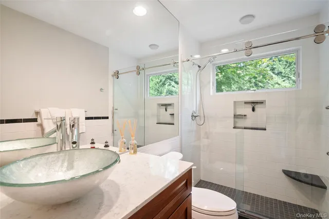 a bathroom with a granite countertop sink toilet a mirror and shower