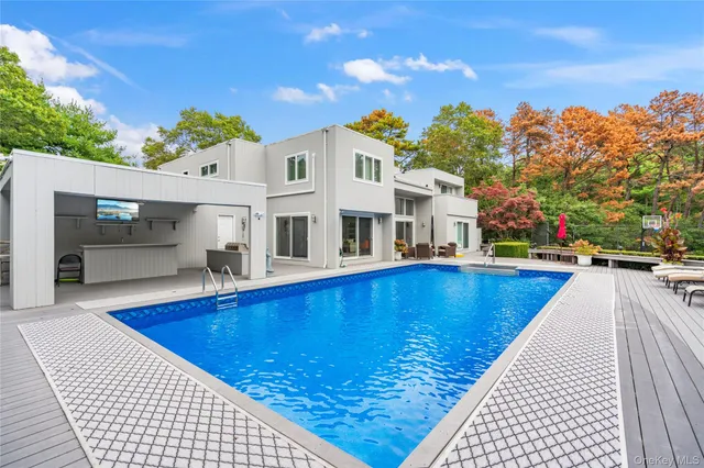a view of swimming pool with outdoor seating and trees in the background