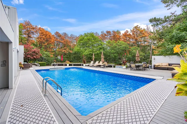 a view of swimming pool with seating space and trees in the background