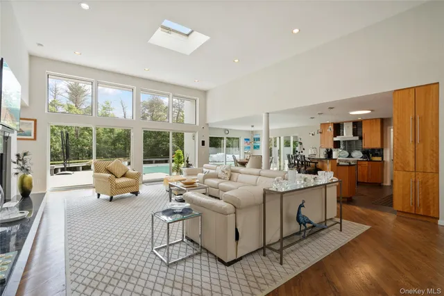 a living room with furniture large windows and wooden floor