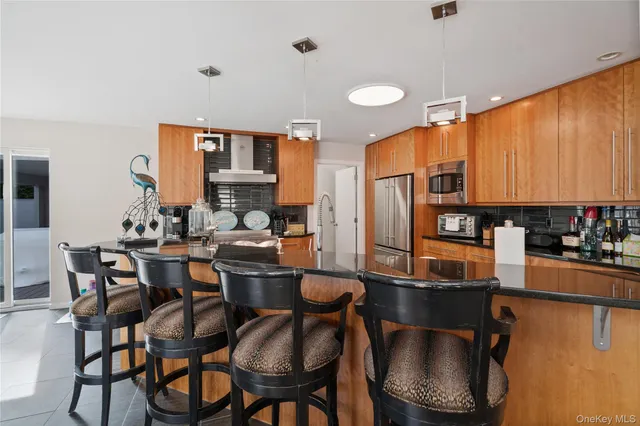 a kitchen with stainless steel appliances kitchen island granite countertop a dining table chairs and sink