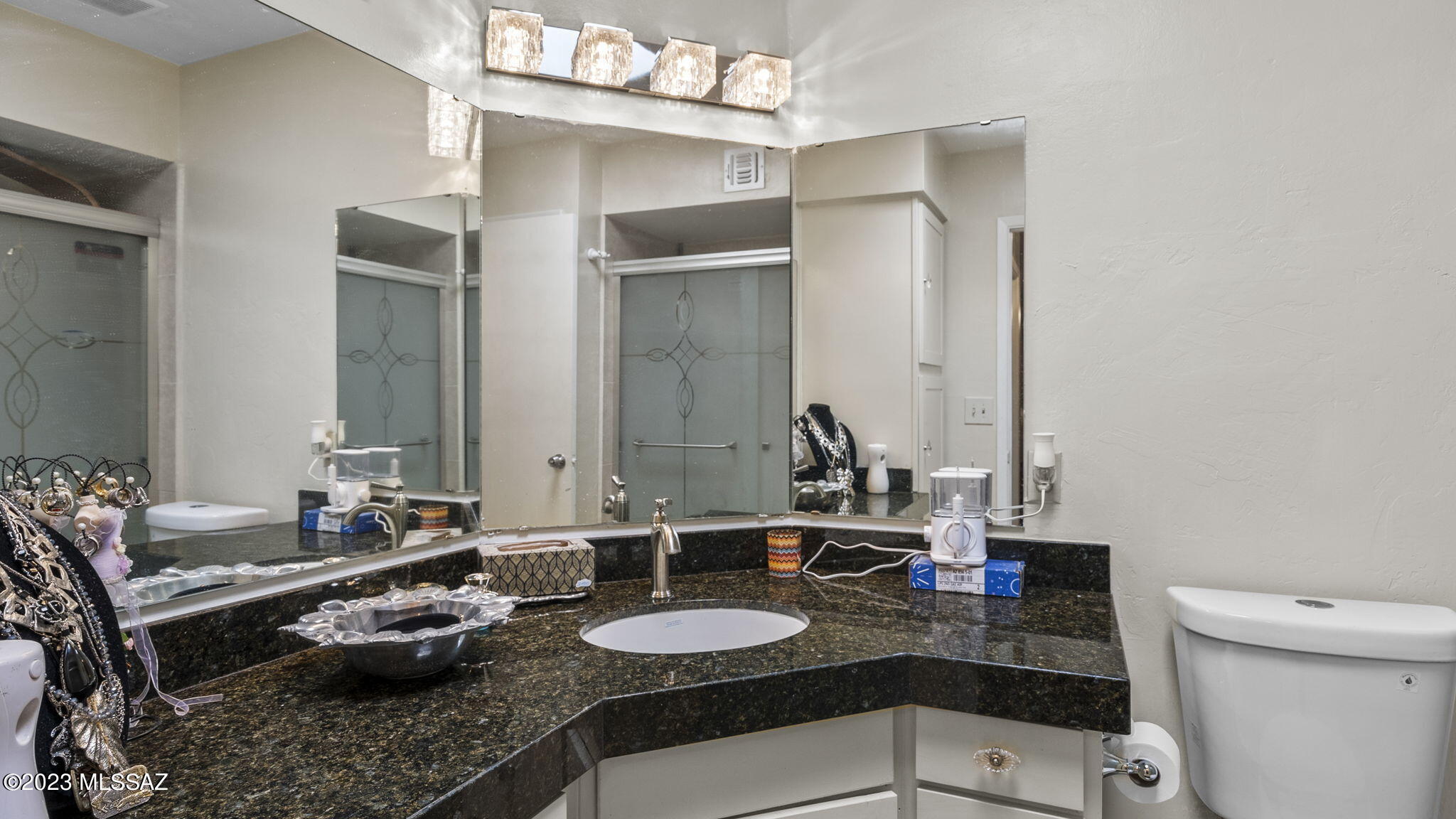 1176 Zircon Court Rio Rico, AZ 85648 - Photo 17 of 26 a bathroom with a granite countertop sink a mirror and a toilet