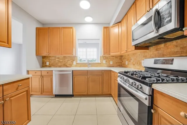 a kitchen with stainless steel appliances granite countertop a stove a sink and a microwave