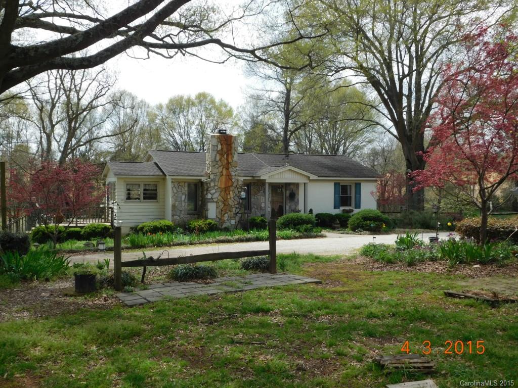 a front view of a house with a yard and large trees