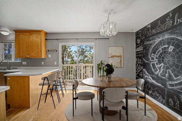 2058 California Avenue, Unit 2 Provo, UT 84606 - Photo 18 of 32 Virtually staged Kitchen and dining area featuring light wood-finish flooring, a white countertop island with seating, natural wood cabinetry, and a black chalkboard wall