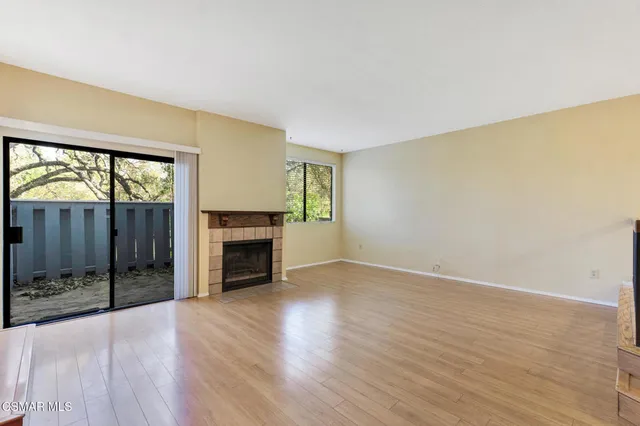 an empty room with wooden floor fireplace and windows