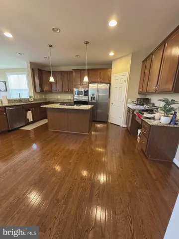 a kitchen with stainless steel appliances granite countertop a sink a stove and a wooden floors