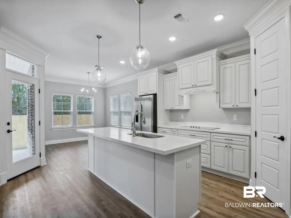 10174 Grady Lane Mobile, AL 36695 - Photo 4 of 14 Kitchen with white cabinets, crown molding, dark wood-type flooring, a center island with sink, and stainless steel fridge