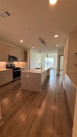 a living room with stainless steel appliances kitchen island hard wood floors and fireplace