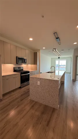 a living room with stainless steel appliances granite countertop furniture wooden floor and a kitchen view
