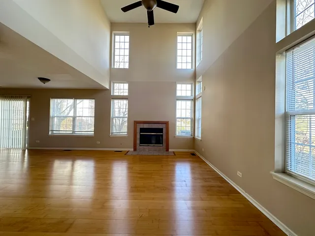 an empty room with wooden floor fireplace and windows