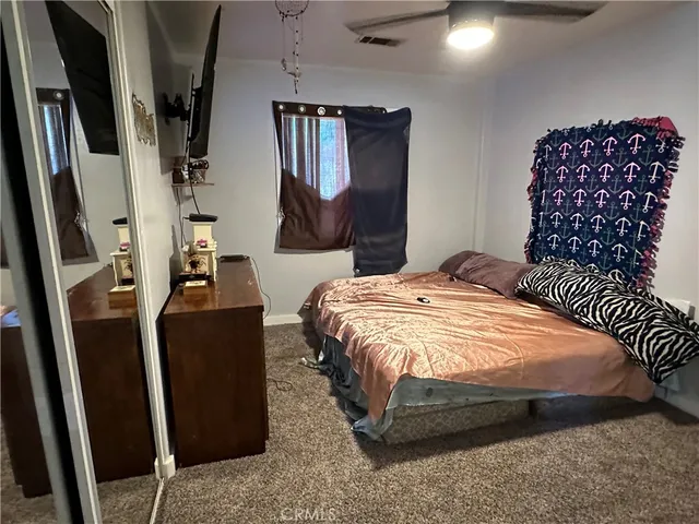 a bedroom with a bed a dresser and potted plant