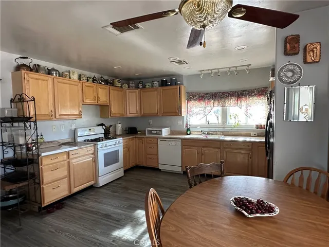 a kitchen with kitchen island granite countertop a stove a sink a refrigerator and white cabinets with wooden floor