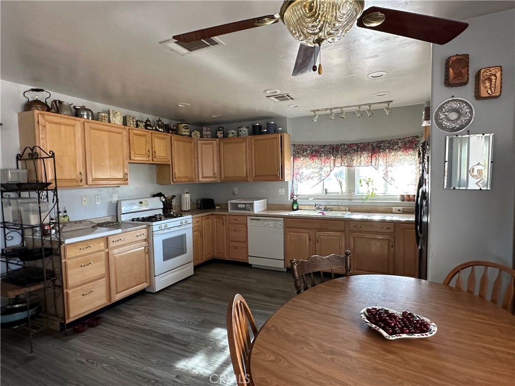 8625 C Avenue Hesperia, CA 92345 - Photo 7 of 29 a kitchen with kitchen island granite countertop a stove a sink a refrigerator and white cabinets with wooden floor