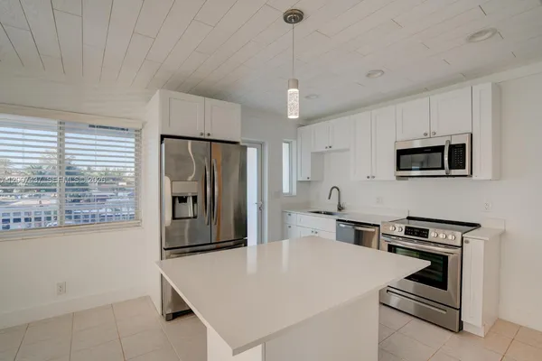 a kitchen with kitchen island a stove a sink and a refrigerator