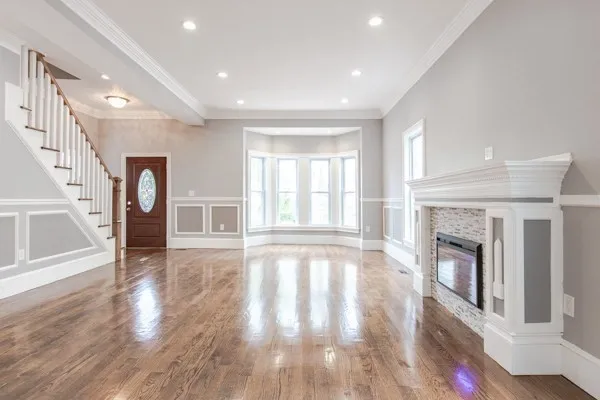 a view of an empty room with wooden floor fireplace and a window