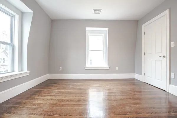 a view of an empty room with wooden floor and a window