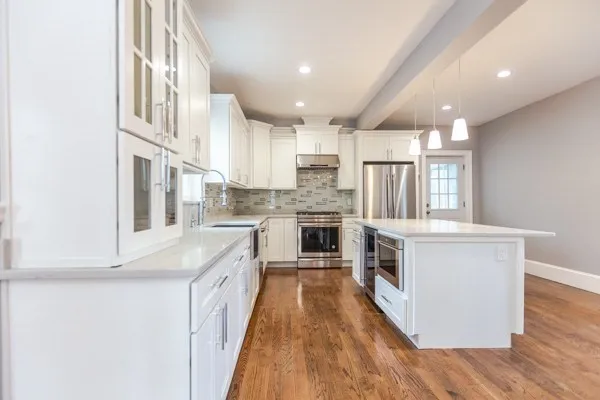 a large kitchen with stainless steel appliances granite countertop a lot of counter space and wooden floors