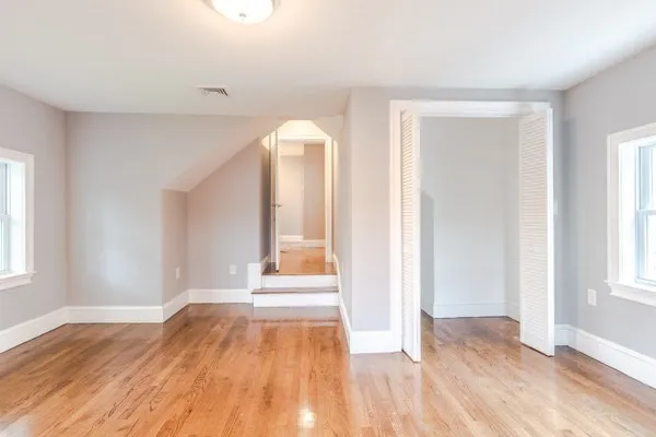 an empty room with wooden floor and windows