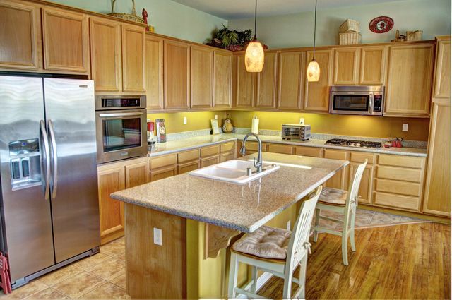 a kitchen with stainless steel appliances granite countertop a sink a microwave refrigerator and chairs