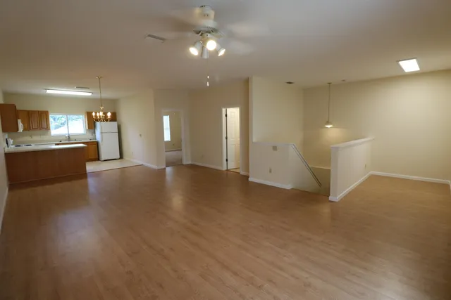 a view of a big room with wooden floor and a kitchen