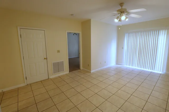 a view of an empty room and chandelier fan