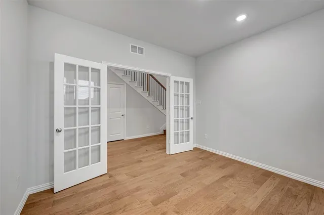 an empty room with wooden floor closet and windows