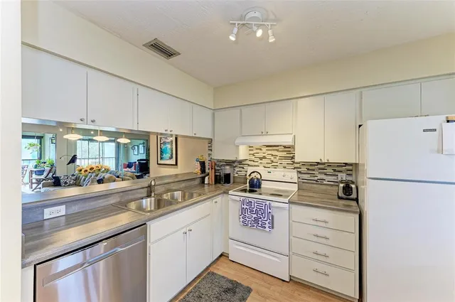 a kitchen with stainless steel appliances a sink a stove and white cabinets