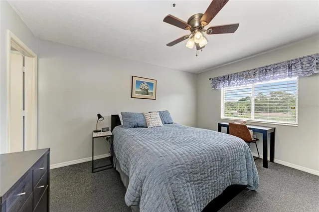 a bedroom with a bed large window with table and chair
