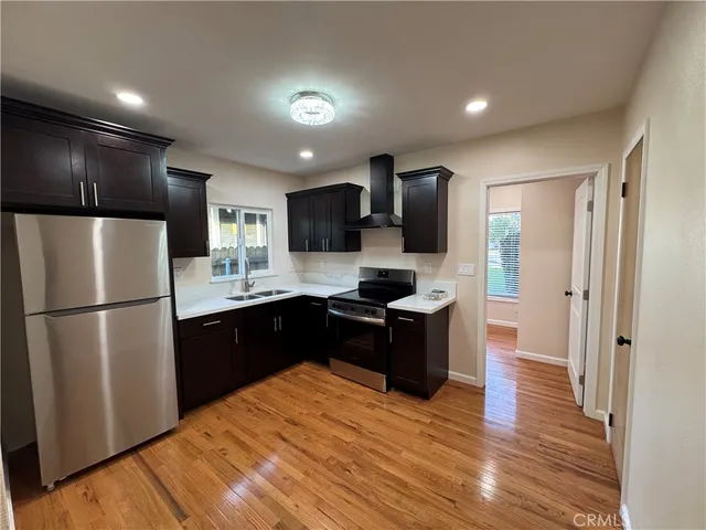 a kitchen with a refrigerator a stove top oven a sink and dishwasher with wooden floor