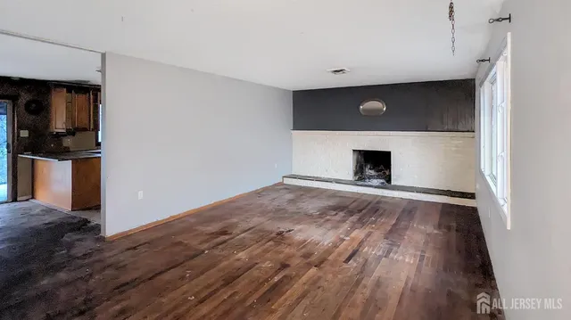 a view of empty room with wooden floor and fireplace