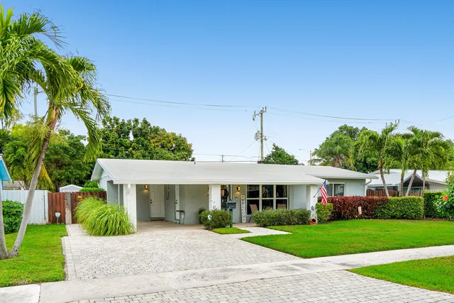 a front view of a house with a garden and trees