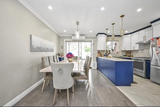 a kitchen with stainless steel appliances kitchen island granite countertop a dining table chairs and a white refrigerator