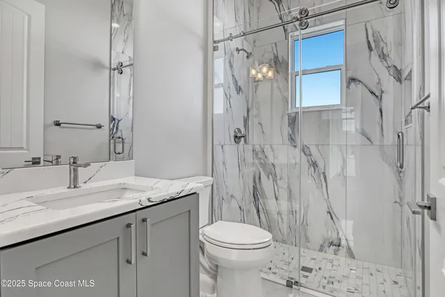 a bathroom with a granite countertop sink toilet and shower