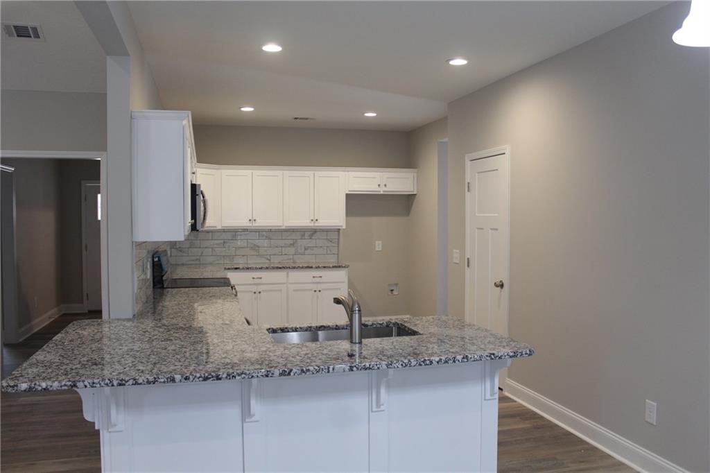 27 Parkman Road Phenix City, AL 36869 - Photo 3 of 11 Kitchen with visible vents, light stone countertops, a peninsula, stainless steel appliances, and a sink