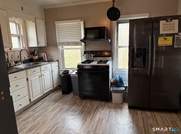 a kitchen with stainless steel appliances a stove a refrigerator a sink and dishwasher with wooden floor