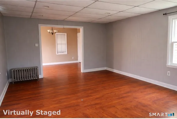 a view of an empty room with wooden floor and a window