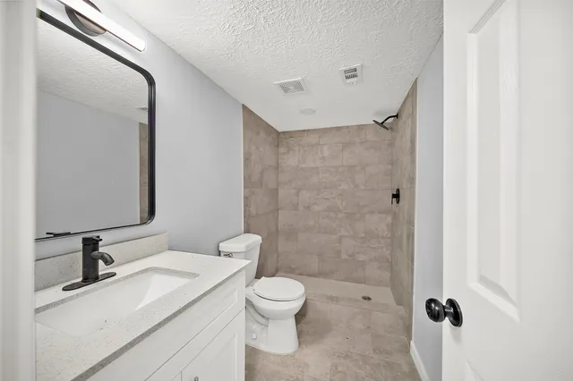 a bathroom with a granite countertop sink toilet a mirror and shower