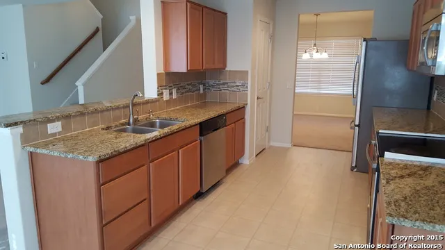 a kitchen with a granite countertop sink and refrigerator