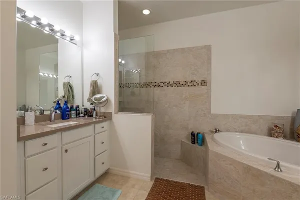 a bathroom with a double vanity sink a mirror a bathtub and