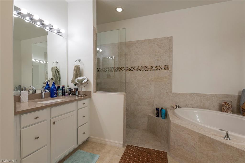 4675 Winged Foot Court, Unit 102 Naples, FL 34114 - Photo 11 of 31 a bathroom with a double vanity sink a mirror a bathtub and