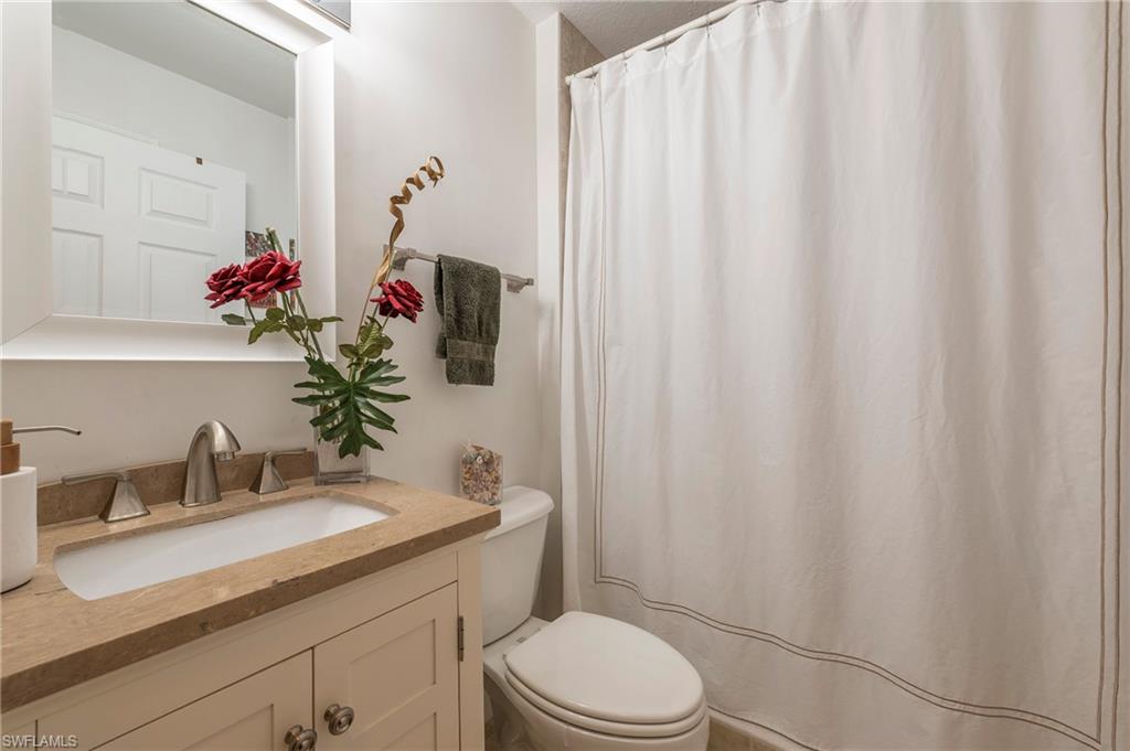 4675 Winged Foot Court, Unit 102 Naples, FL 34114 - Photo 14 of 31 a bathroom with a sink a toilet and shower curtain