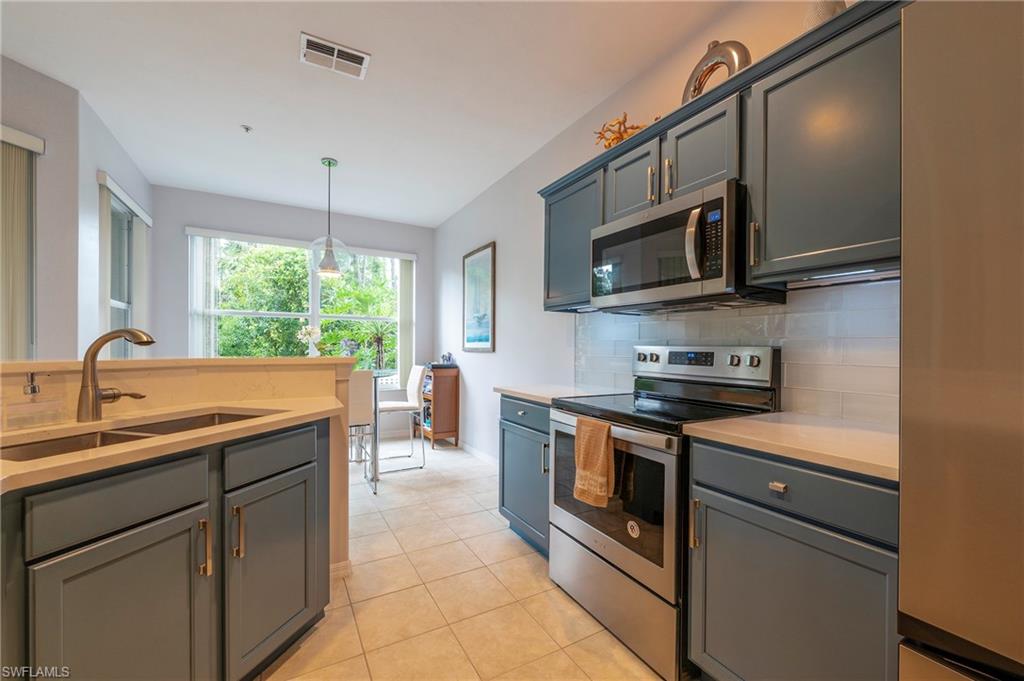 4675 Winged Foot Court, Unit 102 Naples, FL 34114 - Photo 6 of 31 a kitchen with stainless steel appliances granite countertop a sink and stove top oven